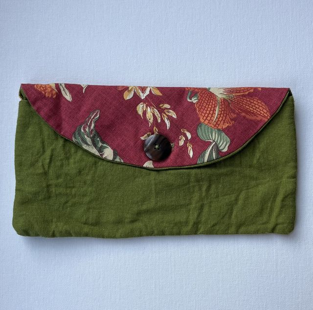Fabric clutch purse of olive green cotton with a dark red floral flap closed by a round button.