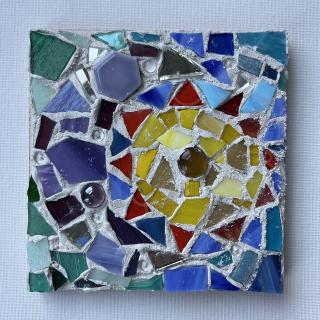 Square mosaic of hand-cut glass, tile and mirror pieces in blues, purples and reds circling a yellow and gold center.